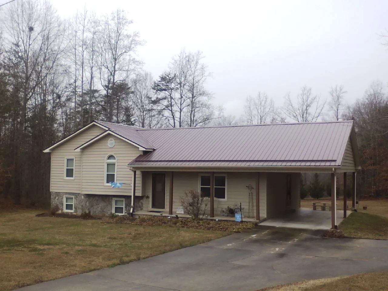 Burgundy metal roof on a tan split level home with an attached carport in Guilderland