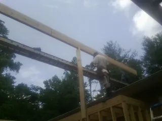Carpenter setting a ridge beam over a new addition frame — Ice Dam Removal by Roofing Brothers in Guilderland