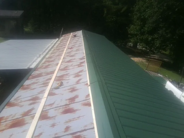Old rusted panels beside newly installed green metal roofing — Wind Damage Roof Repair by Roofing Brothers in Guilderland