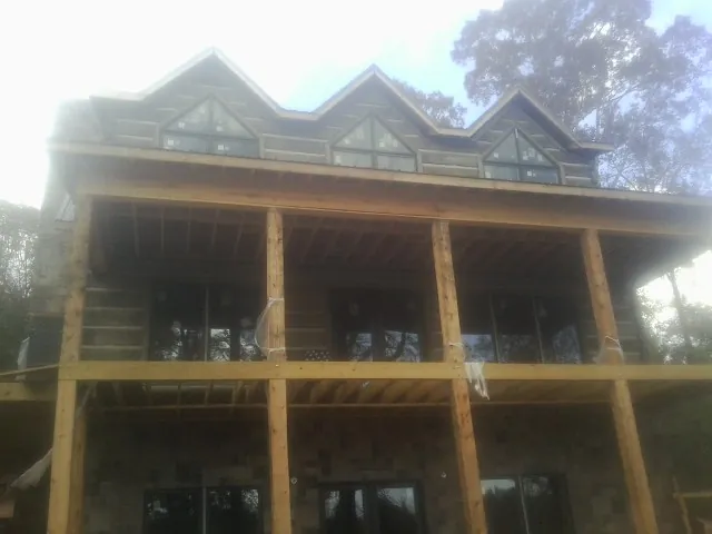 Dormers and porch framing on a large log home under construction — Roof Coating work by our crew in Guilderland